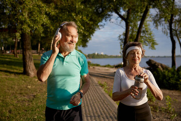 Fototapeta premium Senior man flirting with pretty elderly woman during morning jogging
