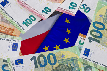 Euro banknotes lying around the flags of Poland and the European Union displayed on a smartphone, concept of cash flow, financing, European funds and contribution to the European budget.