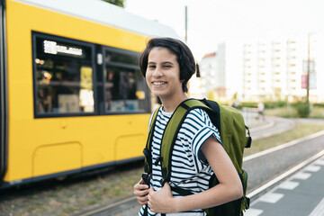 Portrait of happy smiling student waiting for public transportation to school