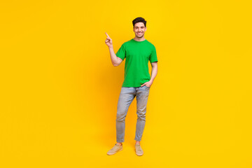 Fototapeta na wymiar Full size photo of cheerful nice guy wear stylish t-shirt indicating at proposition empty space isolated on yellow color background