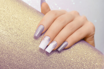 Female hand with long nails with glitter nail polish. Long purple nail design. Women hand with...
