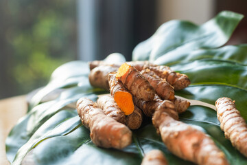 Fresh turmeric roots on a green leaf, close up.