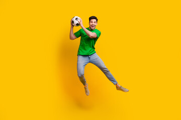 Fototapeta na wymiar Full size photo of excited impressed goalkeeper wear stylish t-shirt jeans catching football ball isolated on yellow color background