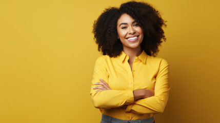 Radiant professional woman in yellow shirt, arms crossed, smiling confidently against a yellow backdrop - obrazy, fototapety, plakaty