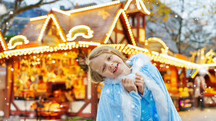 Little smiling girl dressed as a snow princess on Christmas market.