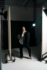 Fototapeta premium Stylish girl posing in a black suit and white shirt in a professional photo studio. Fashion shooting concept