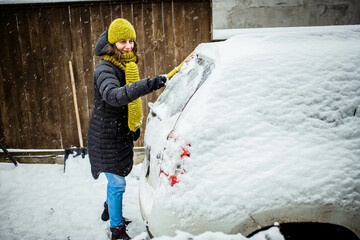 woman cleaning snow from car after blizzard