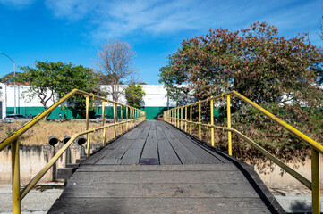 Wooden and iron pedestrian bridge over the Arrudas river in the city of Belo Horizonte. Beautiful blue sky and lots of trees. Horizontal.