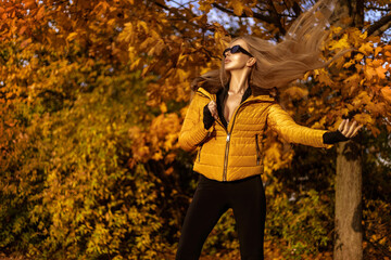 Beautiful woman wearing an winter jacket is posing outdoors on a sunny autumn day.