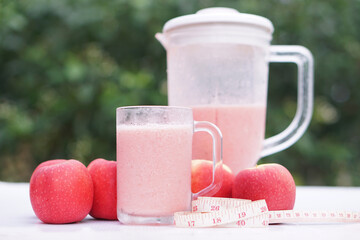 Pink apple fruits smoothie in glass and blender, outdoor background.Concept, healthy beverage for...