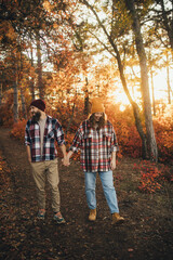Fototapeta na wymiar Happy couple wearing casual clothes walking together in an autumn forest.