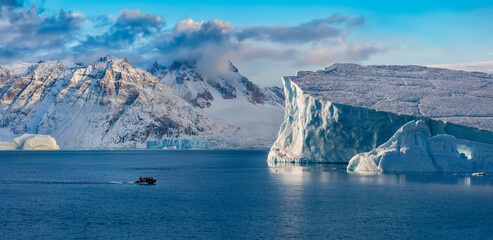 Adventure tourists in Scoresbysund in eastern Greenland in the late afternoon sunlight. - obrazy, fototapety, plakaty