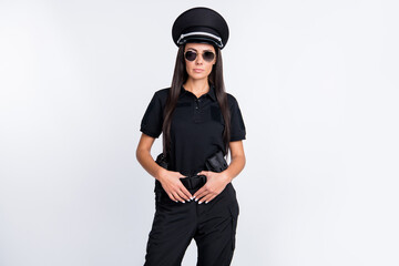 Photo of serious confident young police lady wear black uniform cap dark glasses arms gun belt isolated white color background