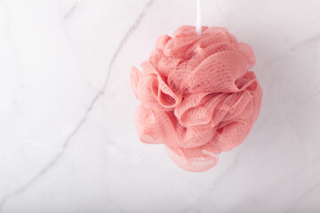 spherical polyester bath sponge hangs on the marble wall.