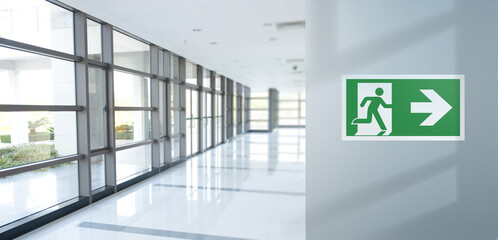Fire exit sign on the right in the corridor of the office. Background space for copy text. Blue...