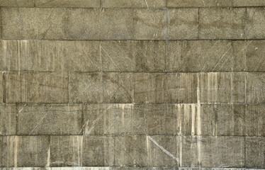 The texture of a wall of large granite tiles that are covered with white streaks when exposed to...