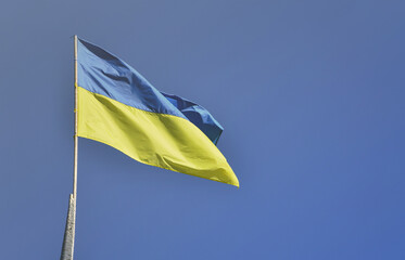 Ukrainian flag against the blue cloudless sky. The official flag of the Ukrainian state includes yellow and blue colors