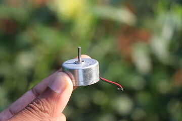 Round dc motor also called as dvd motor held in the hand on a nature background