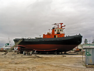 Tugboat, tug-boat or towboat under repairs or maintenance in dry dock at a shipyard