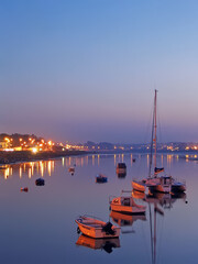 Seixal Bay with small boats and a sailing trimaran at twilight, nightfall, dusk or evening....
