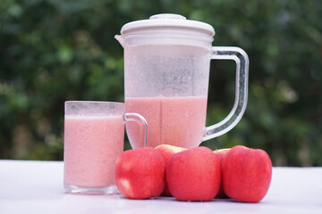Pink apple fruits smoothie in glass and blender, outdoor background.Concept, healthy beverage for...