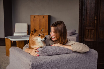 Portrait of cute girl with red Shiba Inu dog at home