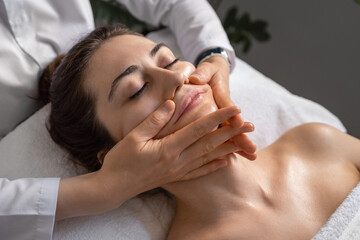 Obraz na płótnie Canvas Pleasant young woman having a foam face massage at spa salon. Spa treatment.