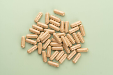 Alternative medicine herbal capsules on green background. Natural herbs and homeopathic supplement product for healthy good life.