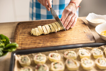 The cook cuts the roulade from the puff pastry into rounds and places it on the tray. - obrazy, fototapety, plakaty