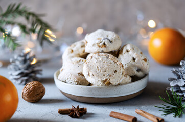 Italian traditional Christmas sweets Cavallucci in ceramic bowl over grey background with xmas decoration, oranges and spices