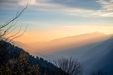 Serene peaceful view of himalaya mountains from Hamta village trek showing hues at dusk sunrise with sun rays passing between mountains in Manali