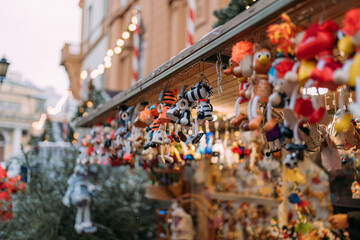 Fototapeta na wymiar Cute shops with Christmas toys and decorations at the New Year city fair. Wooden house with lots of gifts. Christmas trinkets. New Year's crafts