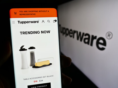 Stuttgart, Germany - 11-10-2023: Person holding smartphone with web page of US home product company Tupperware Brands Corporation with logo. Focus on center of phone display.