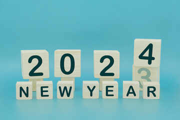 New year 2024 concept. Horizontal woodblocks cubes square with number 2023 change to 2024 on blue...