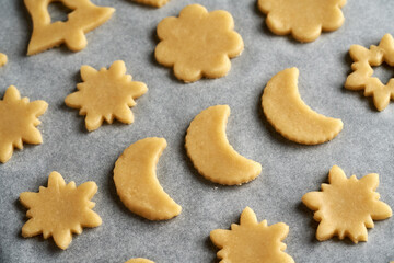 Shapes made of raw pastry dough on baking paper - preparation of Linzer Christmas cookies