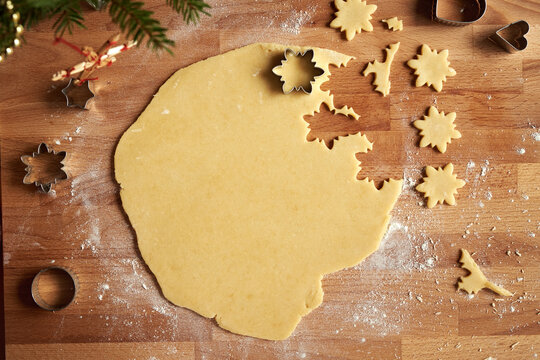 Cutting out shapes from rolled out dough to prepare homemade Linzer Christmas cookies