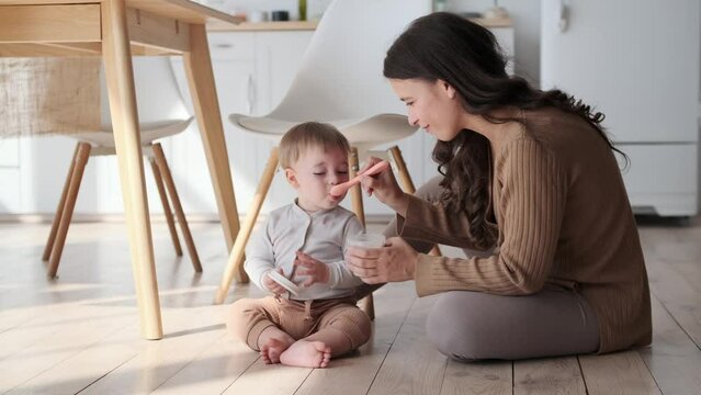 Nurturing mother tenderly feeds little son. Eyes are filled with affection, and the room is hushed, enveloped in the quietude of mealtime moment. This scene captures the essence of maternal care.