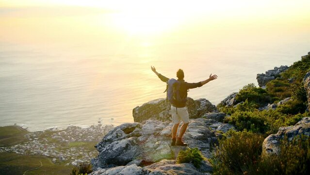 Arms raised, hiking or happy man in celebration on mountain peak in nature adventure walking outdoors on journey. Sunset, view or excited hiker with gratitude for hope or goal achievement by a beach