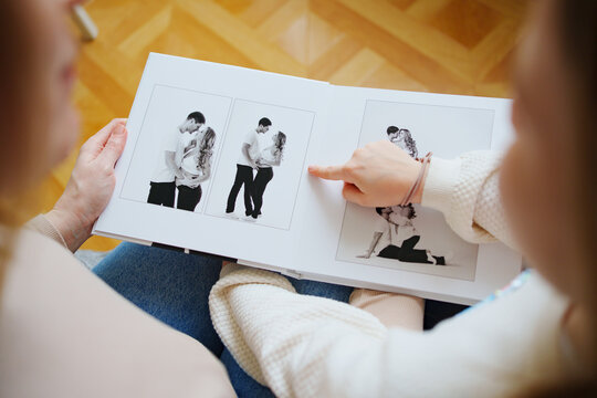 mother and daughter flips through a book with photos of dad and pregnant mom.