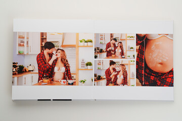 The pages of a photo book with color photos of a pregnant blonde and a man.  - obrazy, fototapety, plakaty
