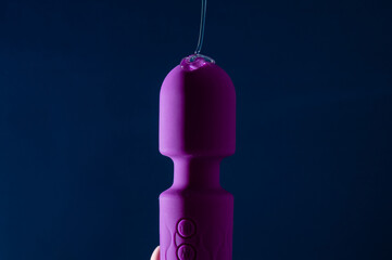 Intimate lubricant pours on a purple vibrator on a blue background. Copy space. 