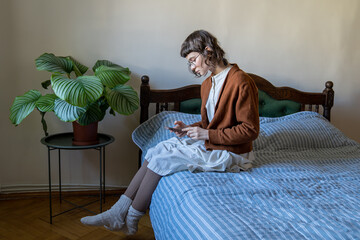 Apathetical teenager spending time alone at home. Unhappy girl scrolling information on smartphone. Addiction to social networks and internet, absence of friends, difficulties in communication  - obrazy, fototapety, plakaty