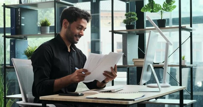 Determined businessman is hard at work in office, diligently tending to computer tasks. His commitment and business acumen shine through as he navigates the digital realm.