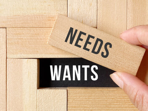 Consumerism Concept - needs vs wants text background. Stock photo.
