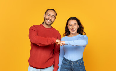 Glad millennial european couple in casual bumping fists