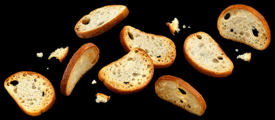 Falling bruschetta crackers, round bread croutons isolated on black background