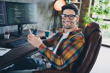 Side portrait of cheerful coder young guy wear shirt sitting armchair browsing smartphone skip his...