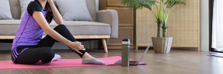 Obraz premium Beautiful healthy woman practicing yoga, Stretch or warm up before exercising, Calming the mind and meditating in her living room, Dumbbells and a protein shake or bottle of water, Healthy exercise.