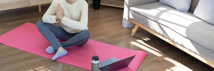 Fototapeta premium Beautiful healthy woman practicing yoga, Stretch or warm up before exercising, Calming the mind and meditating in her living room, Dumbbells and a protein shake or bottle of water, Healthy exercise.