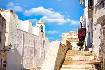 A cobblestone street lined with potted plants. A charming street in Ostuni, Italy, adorned with...